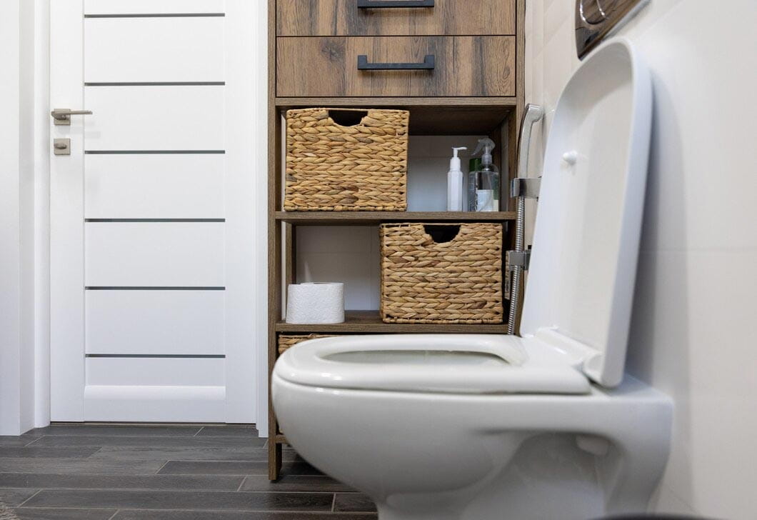 Modern bathroom with a white toilet and wooden storage cabinet
